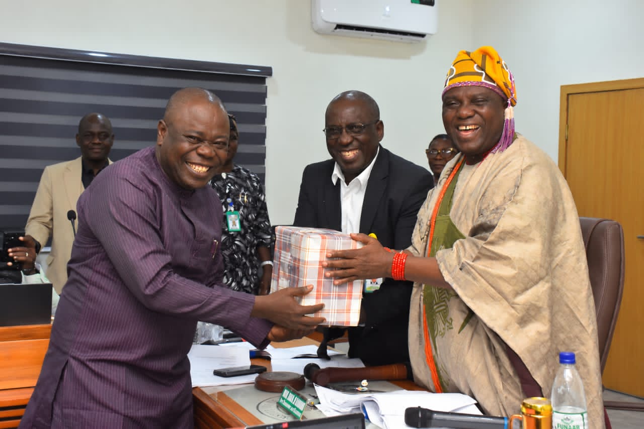 The Pro-Chancellor and Chairman of the Governing Council, HRM, Oba Rasheed Ayotunde Olabomi, Odundun IV, Asoludero, the Aragbiji of Iragbiji Land (Right), being assisted by the Vice-Chancellor, Prof. Babatunde Kehinde to present gifts to the former Council member, Prof. Festus Adeosun at the 117th Statutory meeting of the Council